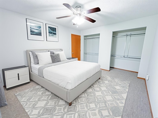 carpeted bedroom with two closets, a ceiling fan, and baseboards