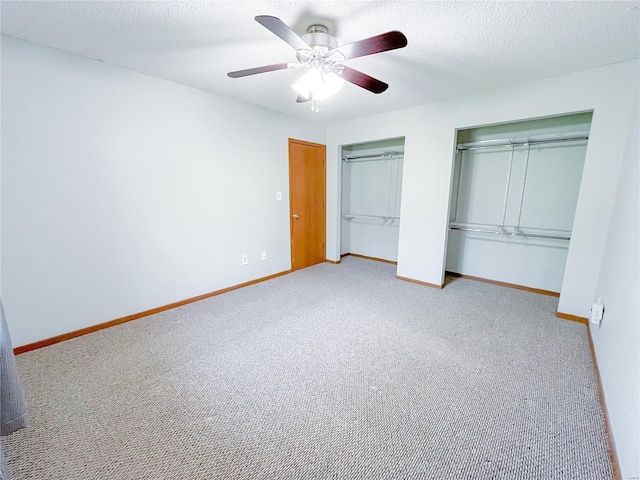 unfurnished bedroom featuring baseboards, carpet flooring, and multiple closets