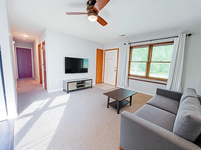 living area featuring baseboards, a ceiling fan, light colored carpet, and visible vents