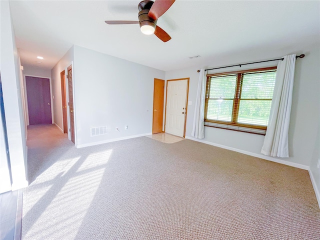 unfurnished room featuring ceiling fan, visible vents, light carpet, and baseboards