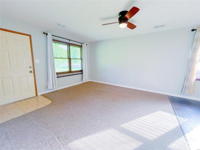 carpeted empty room with visible vents, baseboards, and ceiling fan