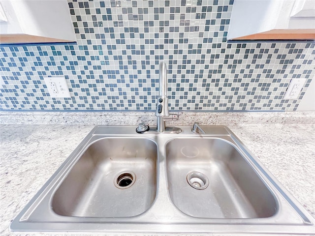 interior details with a sink, light countertops, and backsplash