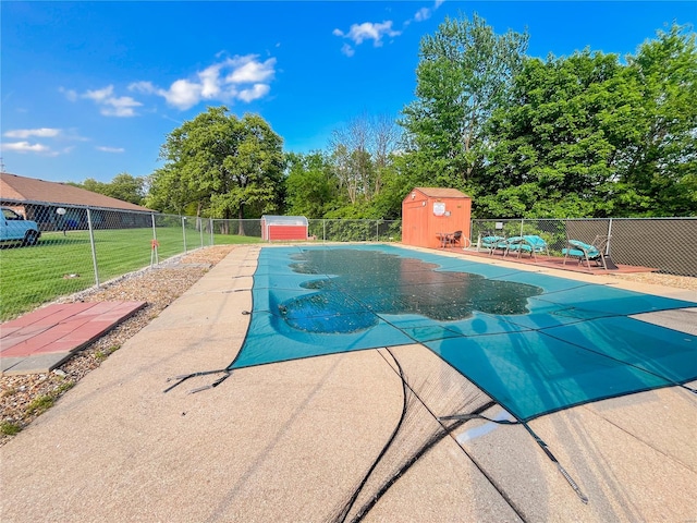 pool featuring a patio area, fence, an outdoor structure, a storage unit, and a yard
