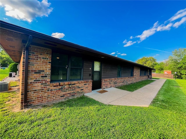 exterior space with brick siding, a yard, and cooling unit