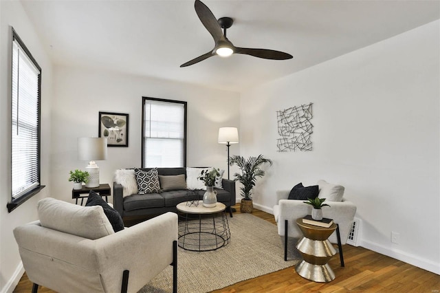 living room featuring baseboards, ceiling fan, and a healthy amount of sunlight