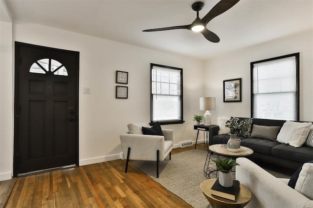 living area featuring ceiling fan, visible vents, baseboards, and dark wood finished floors