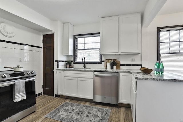 kitchen with a sink, wood finished floors, white cabinets, and stainless steel appliances