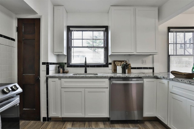 kitchen featuring light stone countertops, dark wood-type flooring, white cabinets, a sink, and appliances with stainless steel finishes