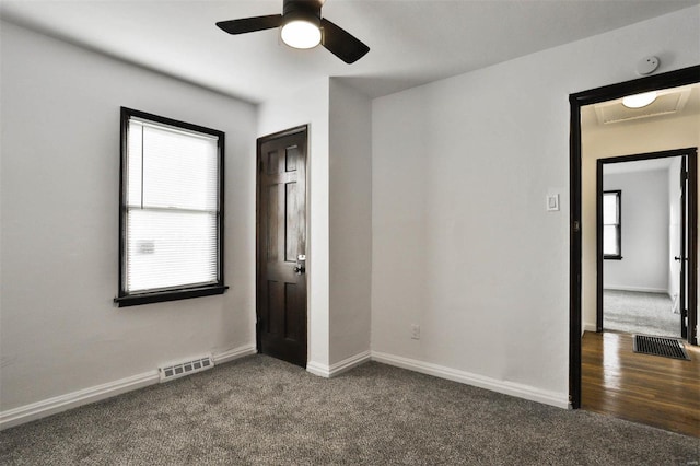 unfurnished bedroom with dark carpet, baseboards, ceiling fan, and visible vents