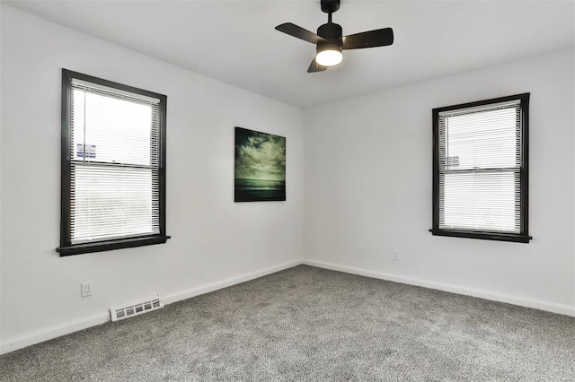 carpeted empty room with a ceiling fan, baseboards, and visible vents