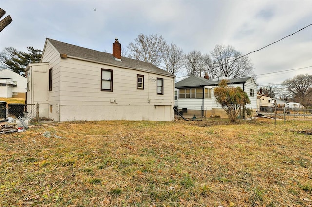 back of property with a yard, fence, and a chimney