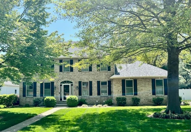 colonial home with a front yard and brick siding