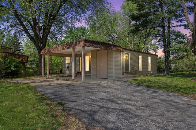 view of front of property featuring a carport, a yard, and aphalt driveway