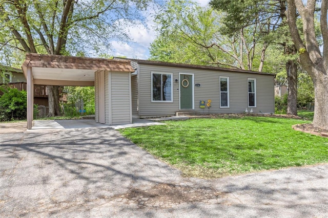 view of front facade featuring entry steps, a carport, a front lawn, and aphalt driveway