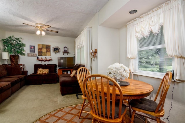 dining space featuring light colored carpet, a textured ceiling, and ceiling fan