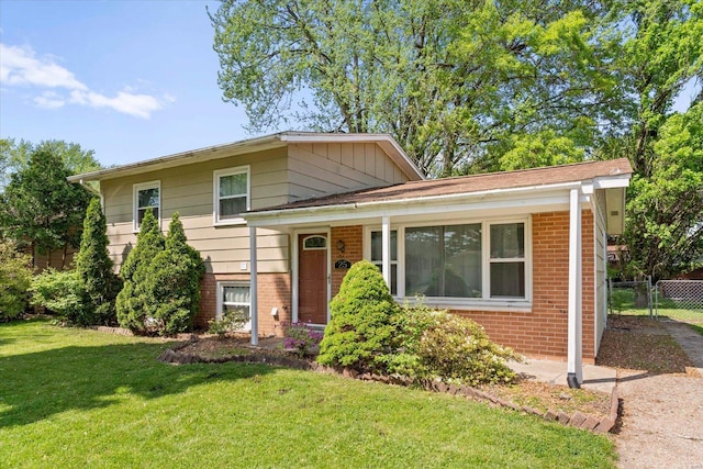 split level home with brick siding, a front lawn, and fence