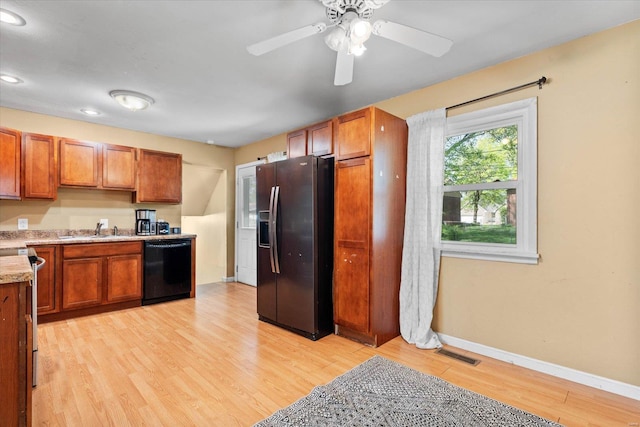 kitchen with stainless steel refrigerator with ice dispenser, visible vents, a sink, baseboards, and black dishwasher
