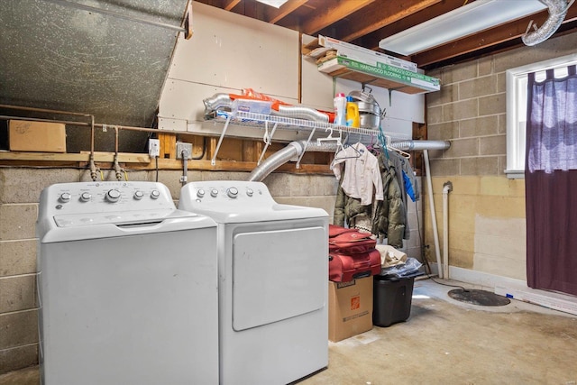 clothes washing area with concrete block wall and washer and clothes dryer