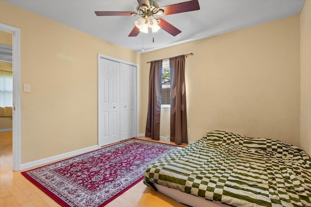 bedroom with a closet, a ceiling fan, baseboards, and wood finished floors