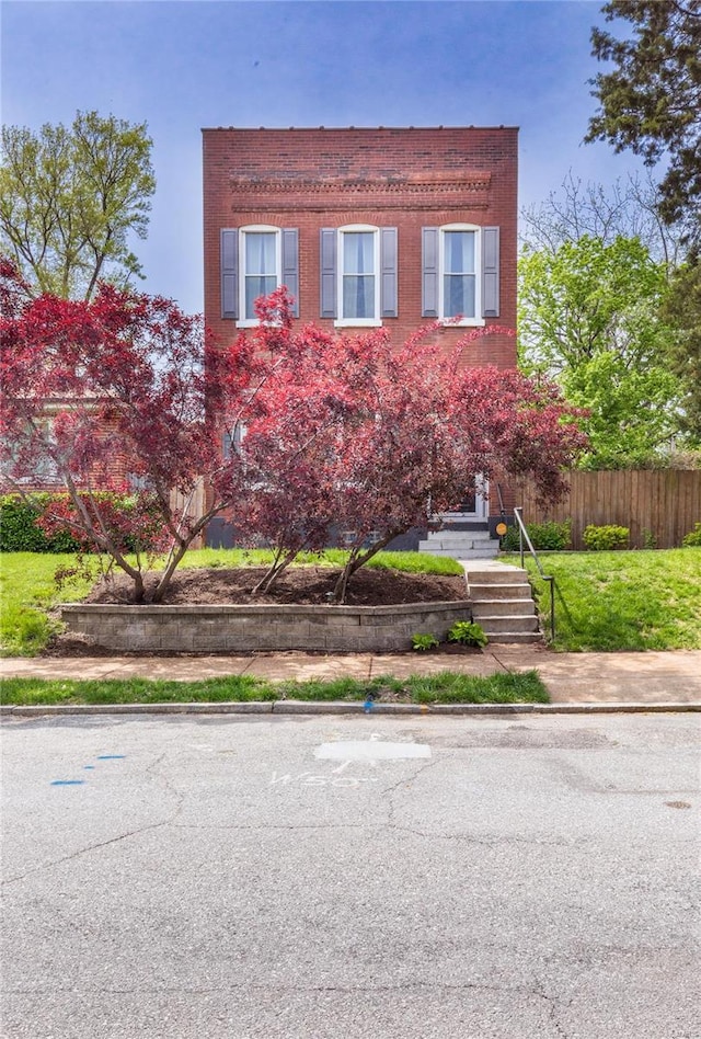 view of front of house with brick siding and fence