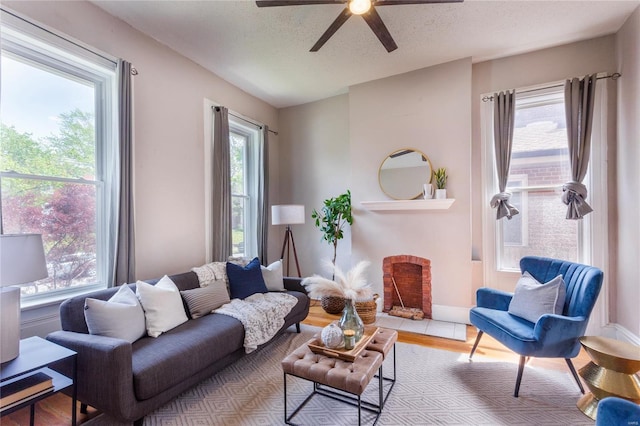 living room featuring baseboards, a ceiling fan, a textured ceiling, and wood finished floors