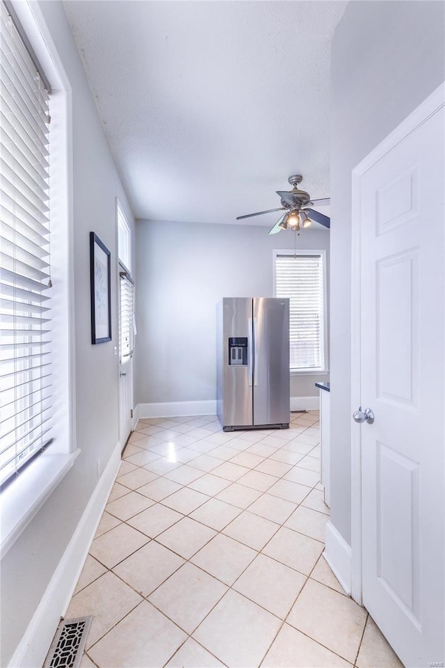 spare room with light tile patterned floors, baseboards, and a ceiling fan