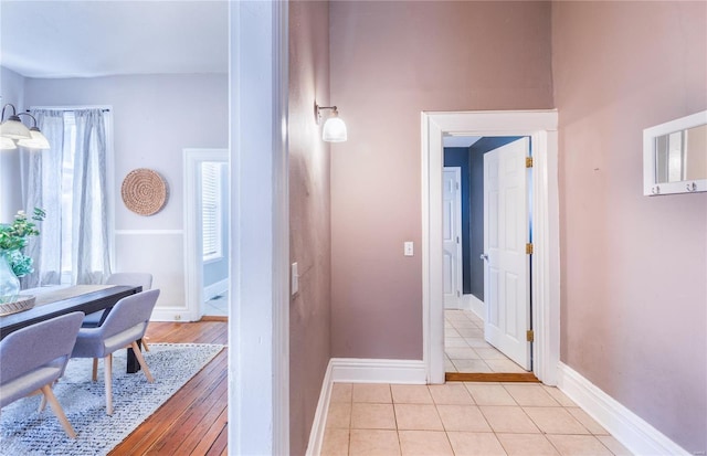 corridor featuring light tile patterned flooring and baseboards