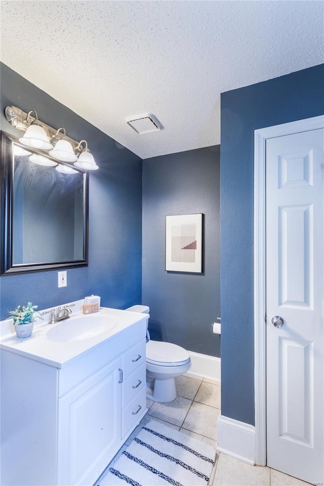 bathroom featuring tile patterned flooring, vanity, toilet, a textured ceiling, and baseboards