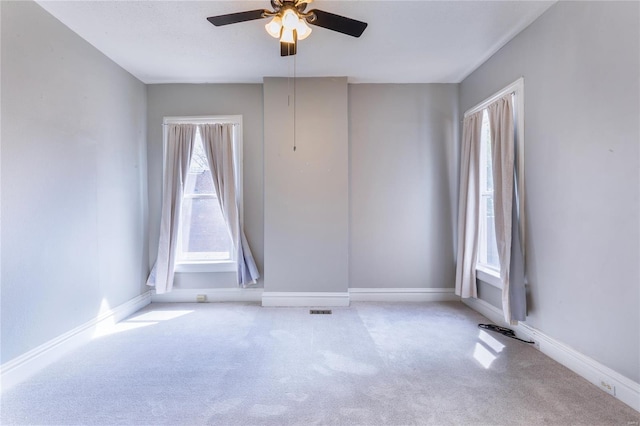 carpeted empty room with ceiling fan and baseboards