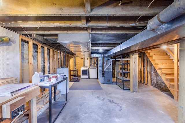 unfinished basement featuring heating unit, independent washer and dryer, and stairway
