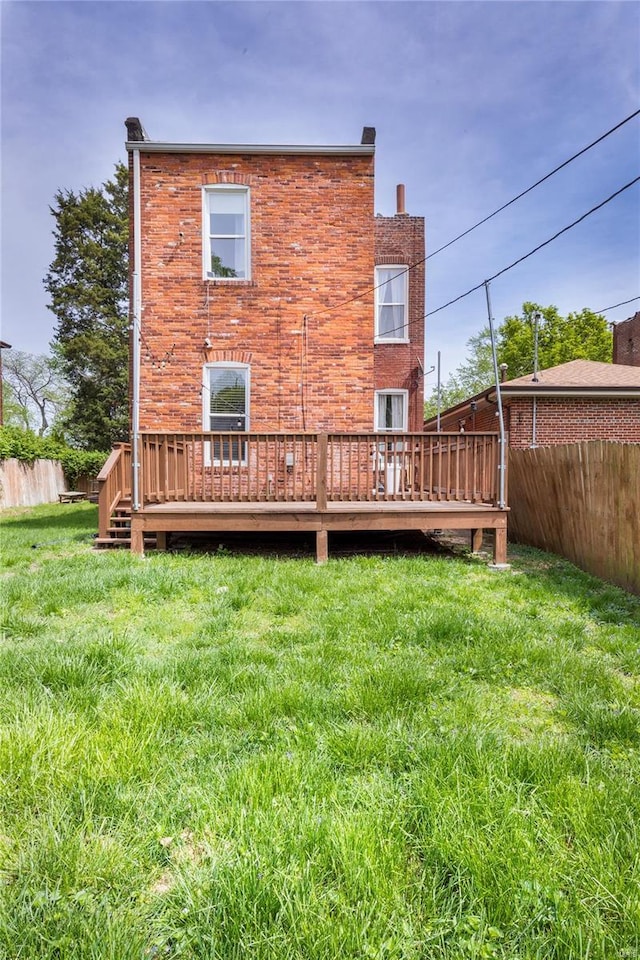 back of property with a yard, a deck, and fence