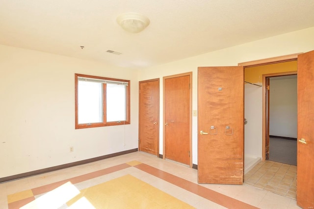 unfurnished bedroom featuring multiple closets, baseboards, and visible vents