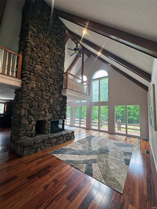 unfurnished living room featuring beamed ceiling, a stone fireplace, ceiling fan, high vaulted ceiling, and hardwood / wood-style flooring