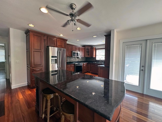 kitchen featuring ceiling fan, appliances with stainless steel finishes, dark wood finished floors, french doors, and glass insert cabinets