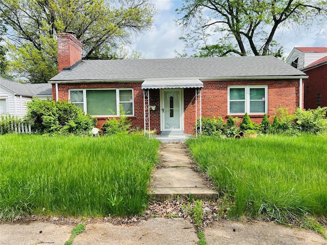 view of front of house featuring roof with shingles, a chimney, and brick siding