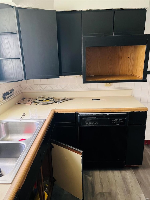 kitchen featuring light countertops, backsplash, black dishwasher, and light wood finished floors