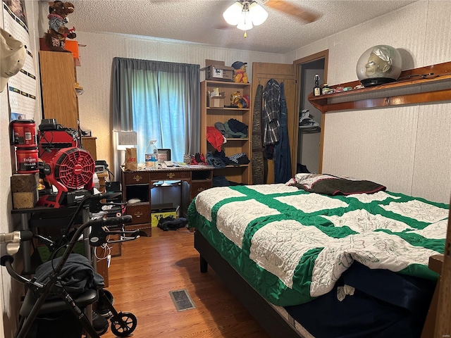 bedroom with visible vents, a textured ceiling, a textured wall, and wood finished floors