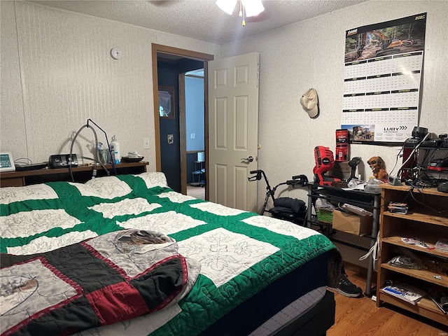 bedroom with a textured ceiling, a textured wall, and wood finished floors