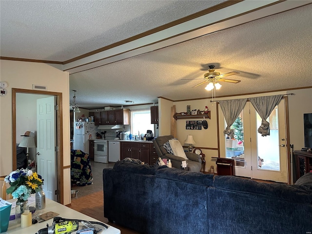 living area with crown molding, ceiling fan, a textured ceiling, and visible vents