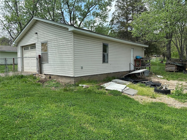 view of side of property with a lawn, fence, and a detached garage