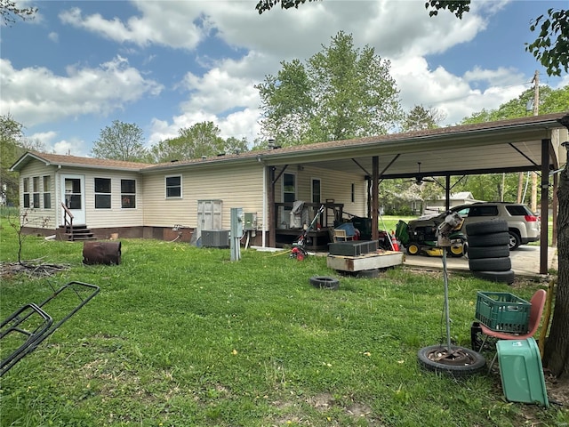 rear view of property with entry steps, an attached carport, a yard, and central AC