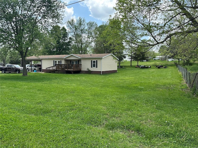 exterior space with fence, a wooden deck, and a front lawn