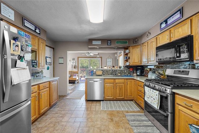 kitchen featuring stone tile floors, a peninsula, light countertops, a sink, and stainless steel appliances