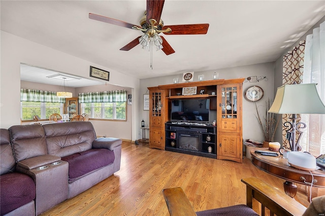 living room featuring baseboards, a ceiling fan, and light wood-style flooring