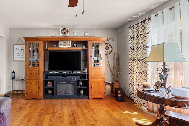 living area with light wood-style floors, baseboards, and ceiling fan