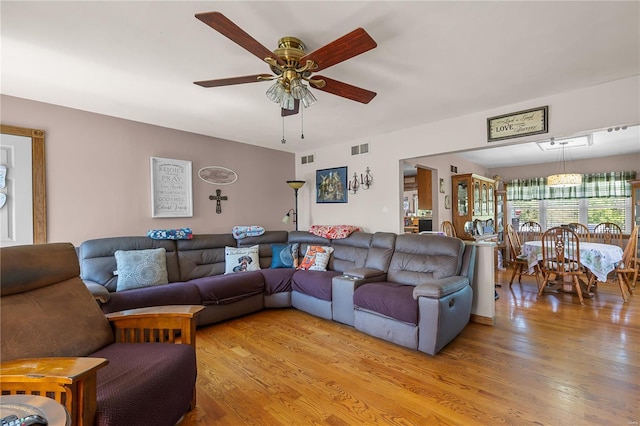 living room featuring light wood-style floors, ceiling fan, and visible vents