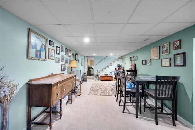 dining room featuring carpet, a drop ceiling, and stairway