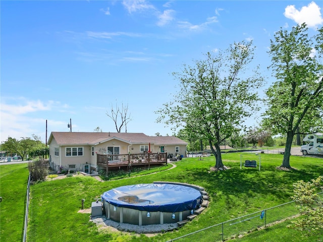 rear view of property with fence, a yard, and a deck