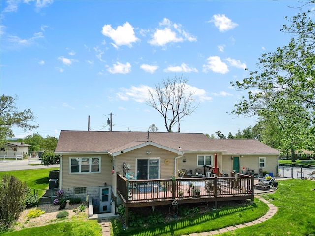 rear view of house featuring roof with shingles, fence, a yard, and a deck