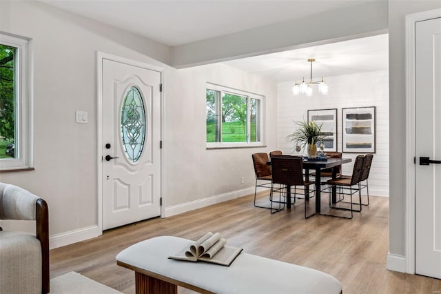 foyer featuring baseboards, a chandelier, and light wood finished floors